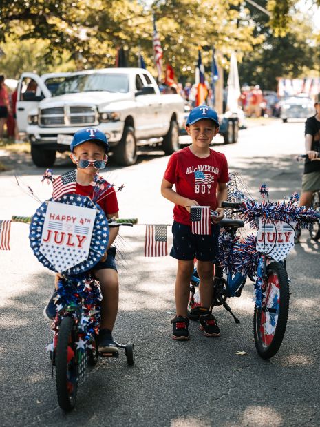 two young boys with bicycles that are decorated in July 4th flags and ribbons