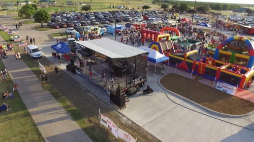high angle view of a small stage with a band performing and inflatable jumping and slide rides for kids in the backgroud
